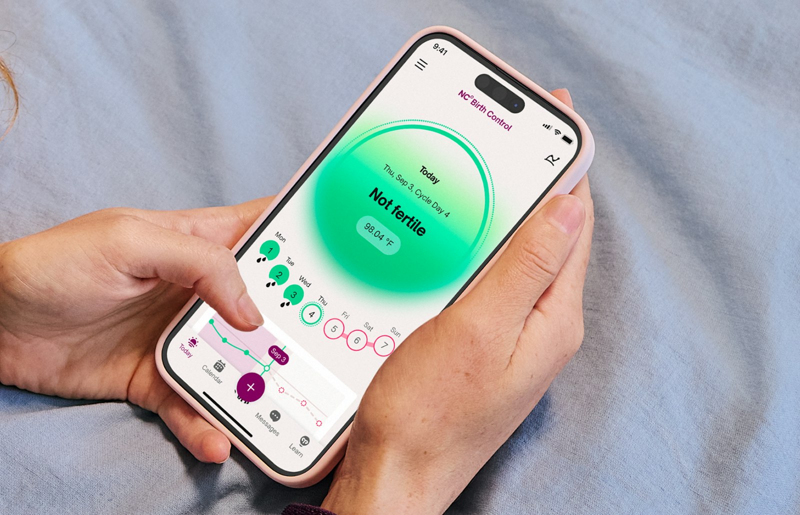Hands holding a phone showing a Not fertile daily status in the NC app